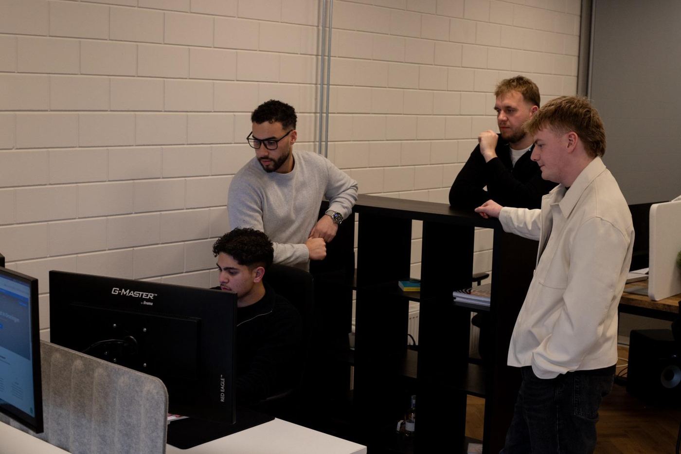 Het team van Collegabouwers kijkt samen naar een scherm op kantoor in Groningen